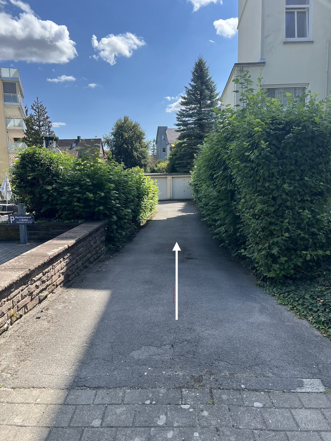 Schmale Zufahrt zum Innenhof mit weißem Pfeil geradeaus
